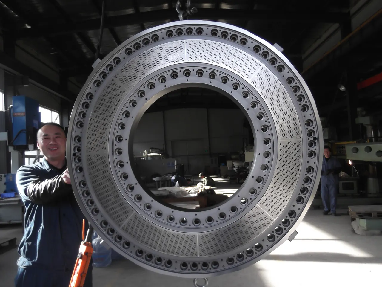 JINFENG technician holding a large pelletizing die plate in the workshop